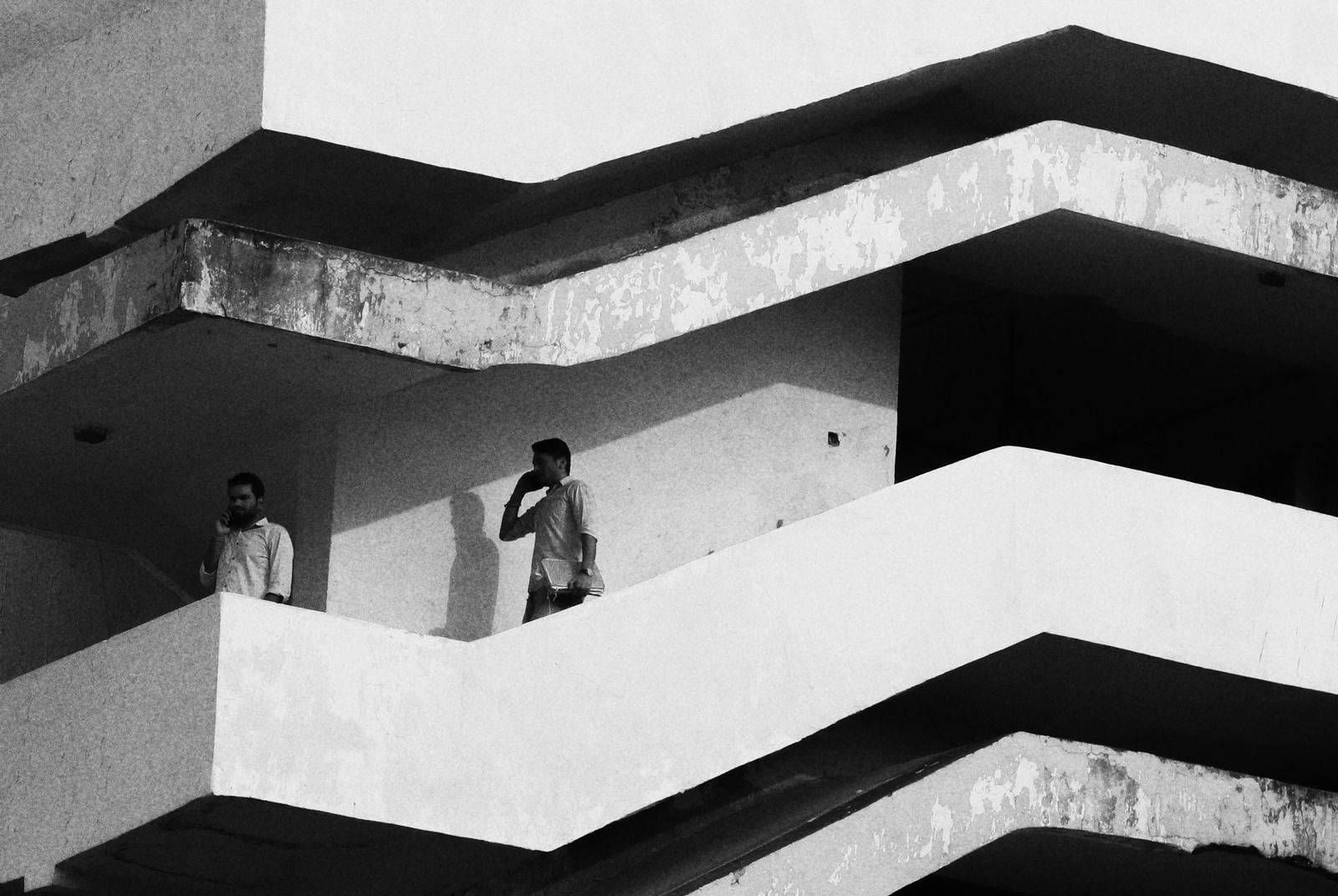 Dos personas hablan por teléfono en balcones separados de un mismo edificio